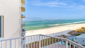 A balcony with a view of a beach and ocean. - Lovely condo at beachfront resort with sunset views, pools, hot tubs, & gym (Panama City Beach)
