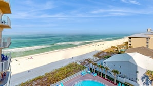 A beachfront hotel with a swimming pool, lounge chairs, and a view of the ocean. - Lovely condo at beachfront resort with sunset views, pools, hot tubs, & gym (Panama City Beach)