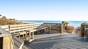 A wooden boardwalk leading to a beach with benches and a small table. - Convenient condo with WiFi, W/D, shared pool, tennis, & bocce, and more (Panama City Beach)