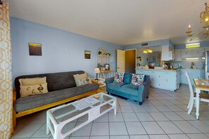 Ein Wohnzimmer mit einer Couch, einem blauen Sofa, einem Couchtisch und einem Essbereich mit Tisch und Stühlen.