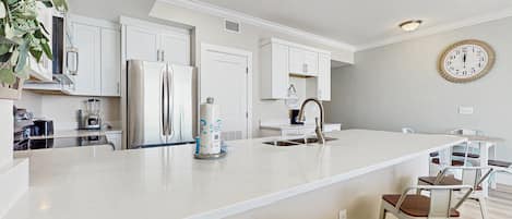 A modern kitchen with white cabinetry, a large island, and bar stools.