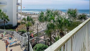 Uma varanda com vista para uma praia, palmeiras e uma bandeira.