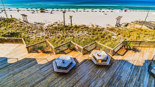 Eine Holzterrasse mit Sitzgelegenheiten und Blick auf den Strand.