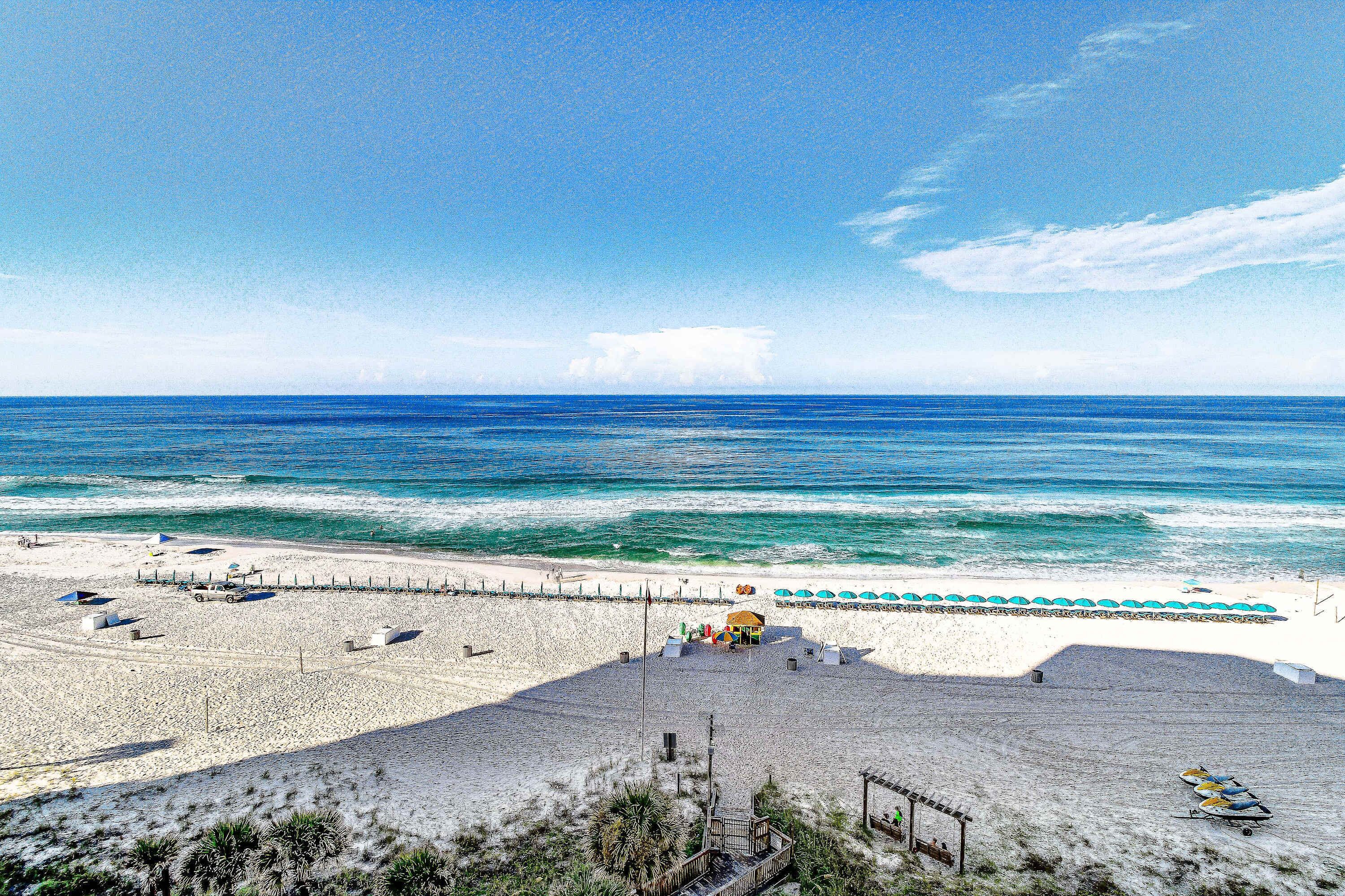 A beach with a sandy area, a small structure, and a few boats.