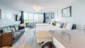 Quarto de hotel com uma cama grande, um sofá, uma escrivaninha e um ventilador de teto.