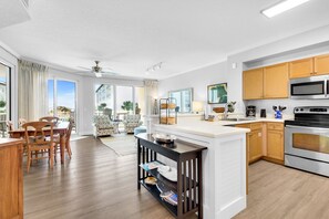 A modern kitchen with a central island, wooden cabinets, and stainless steel appliances. - Super-comfy Seagrove condo with spacious pool-view balcony & pickleball (Santa Rosa Beach)