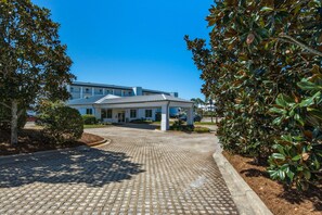 A hotel entrance with a paved driveway leading to a covered walkway. - Super-comfy Seagrove condo with spacious pool-view balcony & pickleball (Santa Rosa Beach)