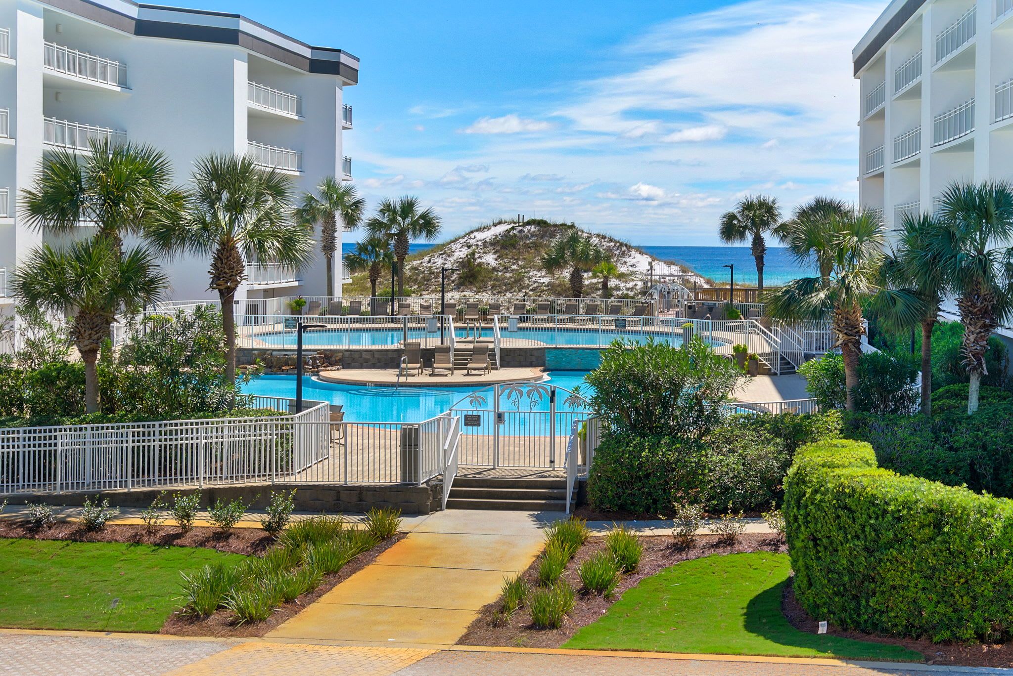 A resort with a swimming pool, palm trees, and a view of the beach.