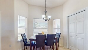 Uma sala de jantar com uma mesa, cadeiras, um candelabro e uma porta.