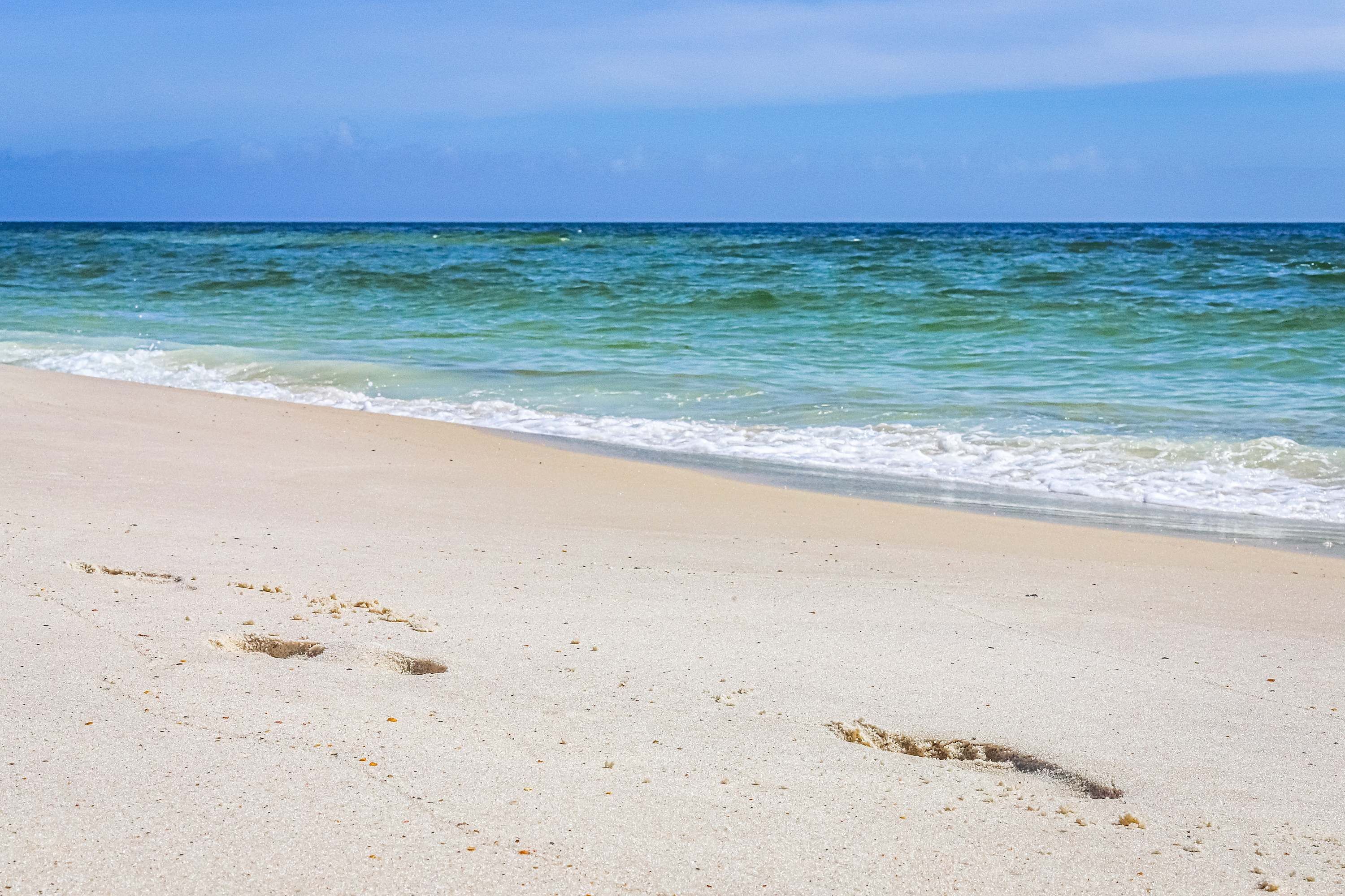 A sandy beach with footprints leading to the water.