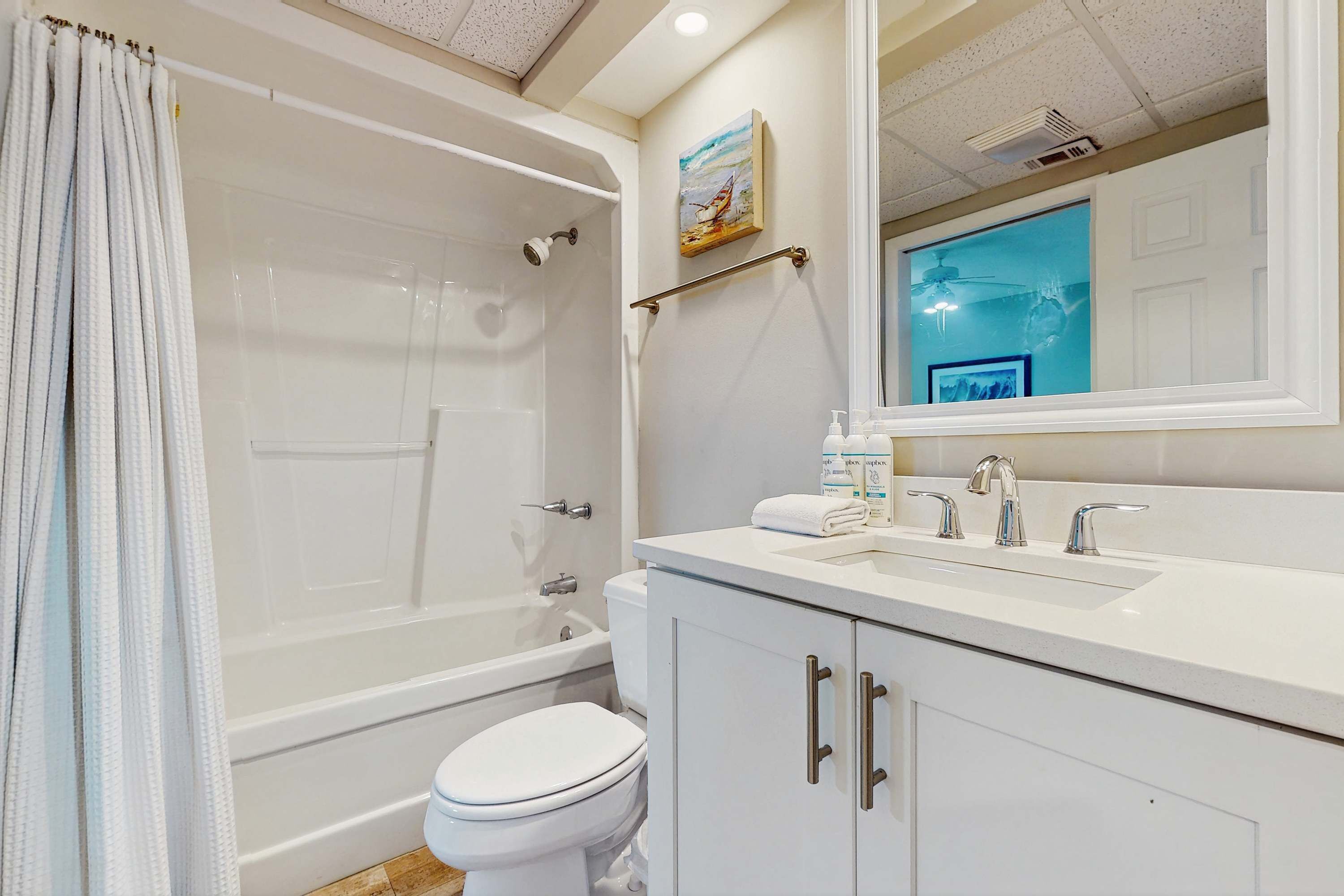 Une salle de bain avec une baignoire, des toilettes et un lavabo avec un miroir au-dessus.