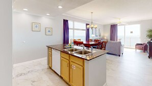 Een moderne keuken met een centraal eiland, een ingebouwde vaatwasser en een eethoek met een tafel en stoelen.