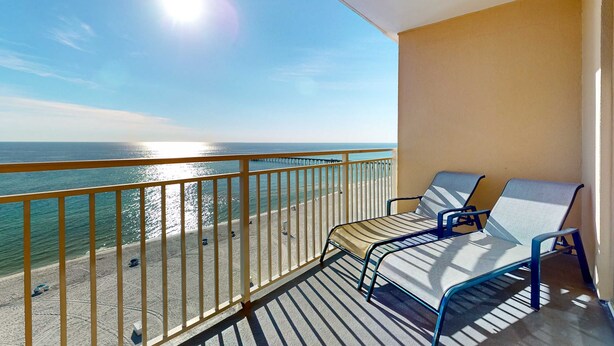 Een balkon met twee loungestoelen, uitzicht op de oceaan en een heldere lucht.
