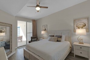 A bedroom with a large bed, a ceiling fan, a nightstand with a lamp, and a view of the outside balcony. - Bright Gulf-view condo with balcony, pool, seasonal beach service & pickleball (Santa Rosa Beach)