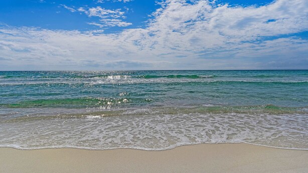 Een strand met helderblauw water en een zandstrand.