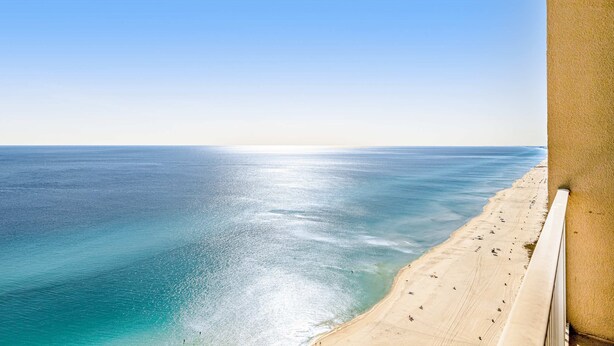 Een uitzicht op de kust met een zandstrand en helderblauwe zee.