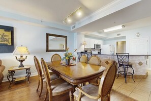 Un coin repas avec une table et des chaises en bois, une lampe et un vase de fleurs.