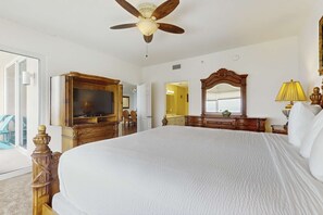 Une chambre spacieuse avec un grand lit, des meubles en bois, un ventilateur de plafond et un téléviseur.