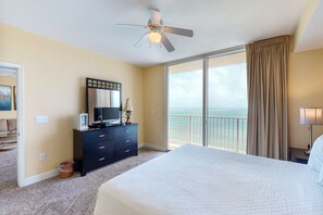 A hotel room with a large bed, a ceiling fan, a dresser with a TV, and a view of the ocean through the balcony doors. - Gulf-front condo w/ 2 lagoon pools, hot tubs & beach service - near Pier Park (Panama City Beach)