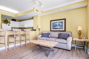A living room with a sofa, coffee table, and two chairs. There is a kitchen area with cabinets and a microwave. - Gulf-front condo on the 16th floor w/ pools, hot tubs & seasonal beach service (Panama City Beach)