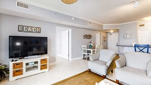 Una sala de estar con una televisión, un sofá, una mesa de comedor con sillas y un letrero que dice 'BEACH'.