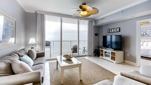 Una sala de estar moderna con sofá, una mesa de centro, televisor y un balcón con vistas.