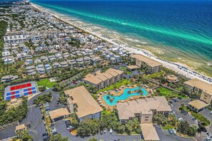 Luftaufnahme eines Küstenresorts mit Pool, Strand und mehreren Gebäuden.
