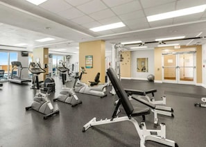 Un gimnasio con diversos equipos de ejercicio, incluyendo cintas de correr y máquinas de pesas.