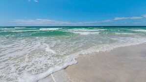 Una playa con agua turquesa cristalina y olas de espuma blanca.