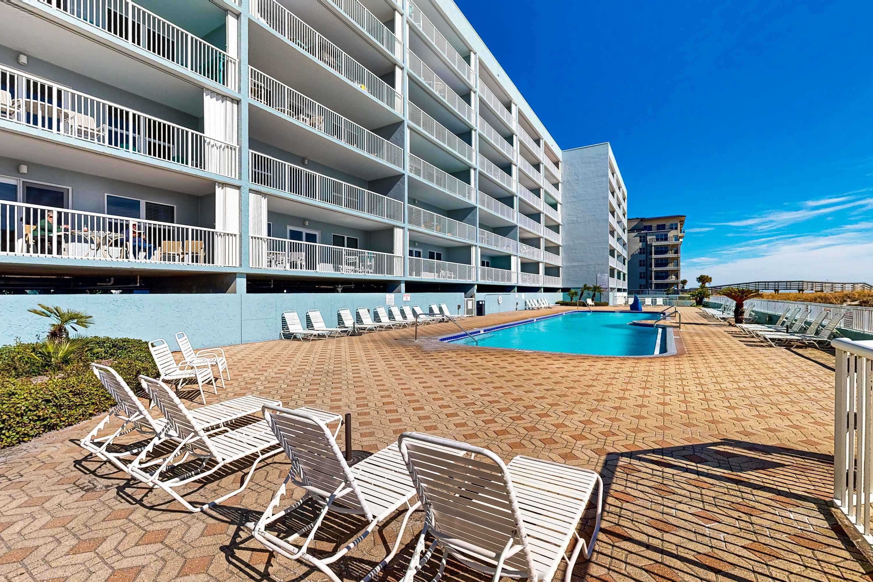 A hotel with a swimming pool, multiple balconies, and outdoor seating areas.