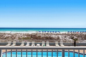 A poolside view with a beach in the background, lounge chairs, and a 'NO DIVING' sign. - Spacious condo in with free WiFi, pool access, central AC, and washer&dryer (Fort Walton Beach)