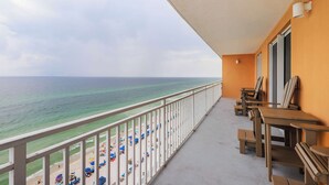 En balkon med udsigt over stranden og havet, møbler af træ og et gelænder.