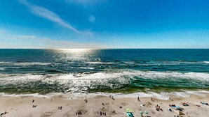 Une plage avec des gens et des parasols, un ciel dégagé et l’océan.