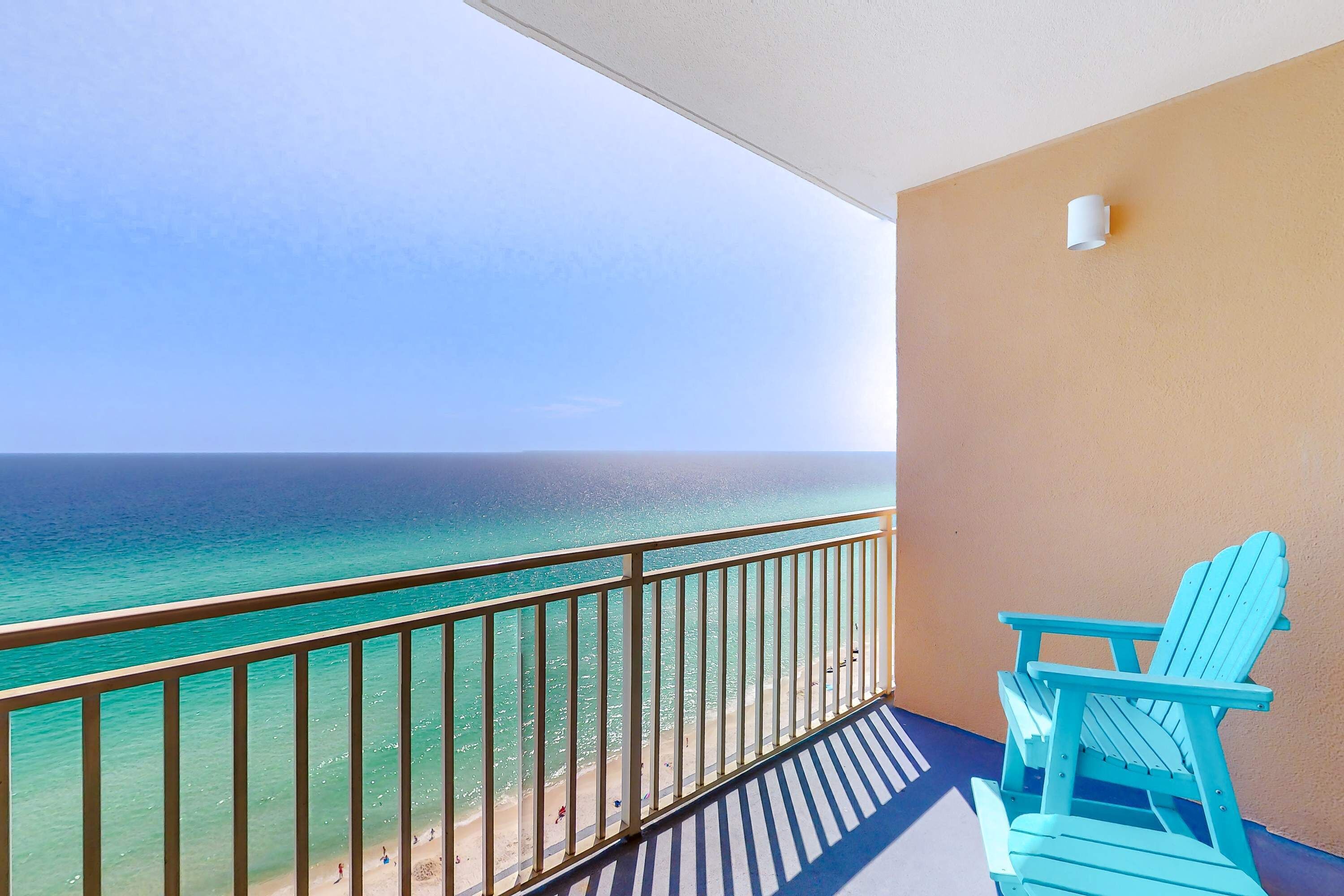 Un balcone con vista sull'oceano, una sedia e un punto luce fissato al muro.
