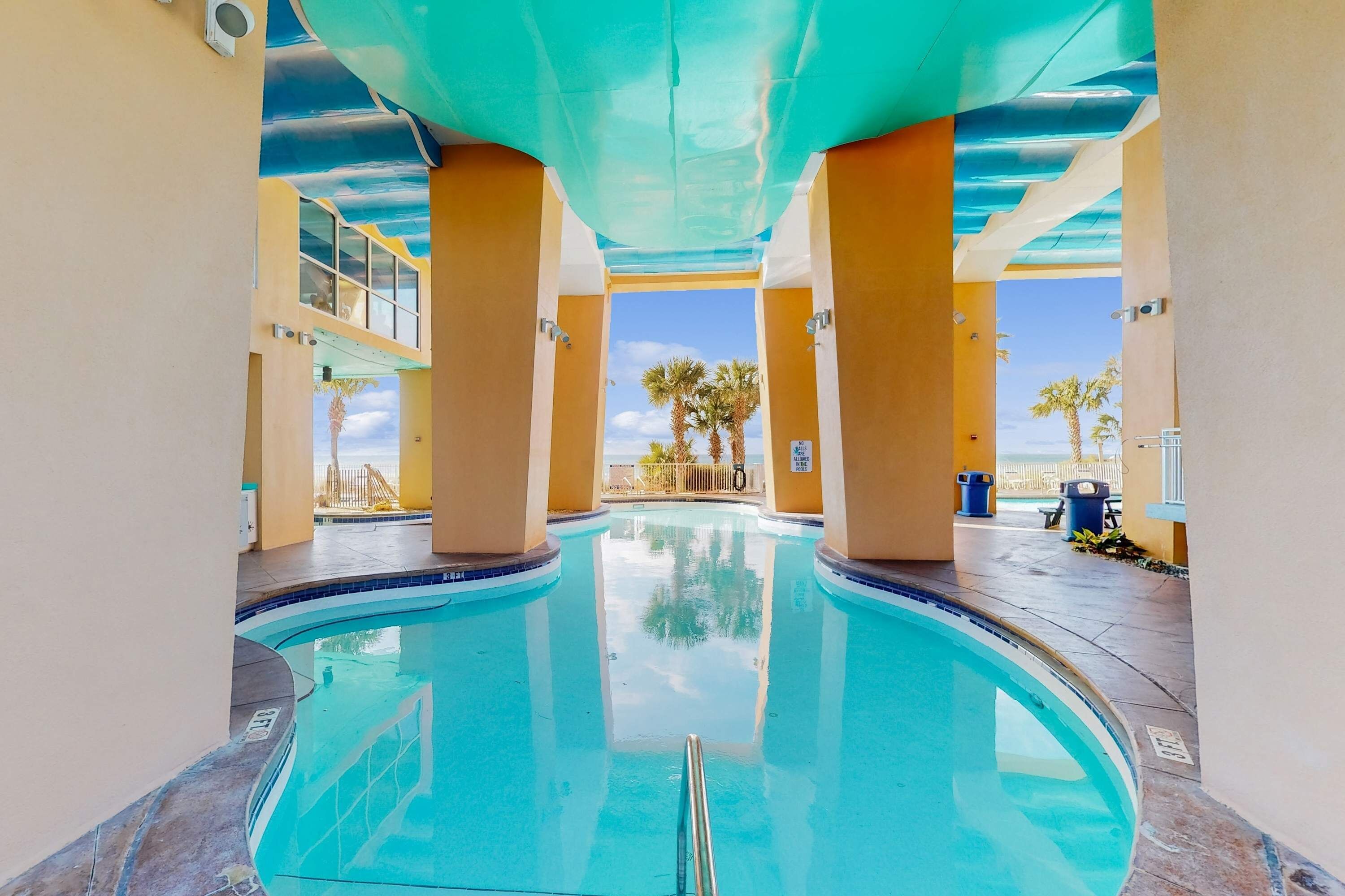Une piscine offrant une vue dégagée sur les palmiers et une plage lointaine.