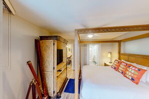 A hotel room with a large bed, a wooden wardrobe, a telescope, and a desk with a lamp. - Gulf-front condo with pools, hot tub, tennis & pickleball - steps to the beach (Panama City Beach)
