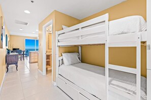 Een slaapkamer met stapelbed en uitzicht op zee door een raam.
