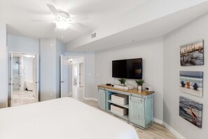 A bedroom with a bed, a ceiling fan, a TV, a dresser, and artwork on the wall. - Gorgeous condo with pool & Gulf view, stunning decor, bunk beds & pickleball (Santa Rosa Beach)