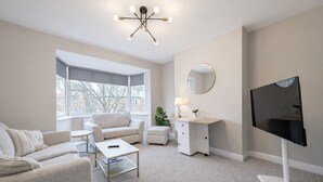 A modern living room with a sofa, a coffee table, a TV, a desk, and a large window. - 2 Bed Flat, Newcastle, 5 min to City, Free parking - Pass the Keys (Newcastle)