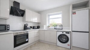 A modern kitchen with white cabinetry, a built-in oven, a microwave, a coffee maker, and a washing machine. - 2 Bed Flat, Newcastle, 5 min to City, Free parking - Pass the Keys (Newcastle)