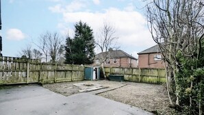 A backyard with a concrete patio, a wooden fence, and a small shed. - 2 Bed Flat, Newcastle, 5 min to City, Free parking - Pass the Keys (Newcastle)