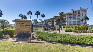 Schild des Grand Caribbean West Hotels mit Blick auf die umliegenden Gebäude und Palmen.