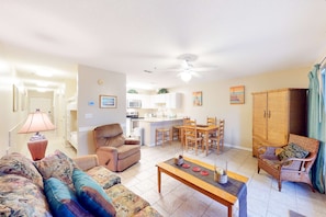 Sala de estar con sofá, sillón y mesa de centro. Zona de cocina con microondas, estufa y mesa de comedor.