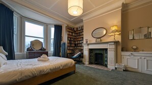 Ein Schlafzimmer mit einem großen Bett, einem Kamin, einer Bücherwand und einem Spiegel.