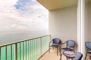 A balcony with a view of the sea, two chairs, and a small table. - Warm & welcoming condo w/Gulf and beach views, on-site pools & hot tub (Panama City Beach)