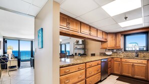 Une cuisine moderne avec des meubles en bois, des plans de travail en granit et un lave-vaisselle encastré.