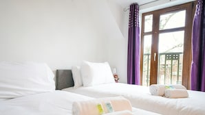 Ein Hotelzimmer mit zwei Betten, weißer Bettwäsche und violetten Vorhängen.