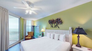 A hotel room with a bed, a nightstand, a lamp, a chair, and a view of the ocean. - Coastal condo steps to beach with pools, hot tub, gym & amazing views (Perdido Key)