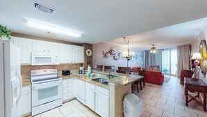 A modern kitchen with white cabinets, a built-in oven, and a granite countertop. - Coastal condo steps to beach with pools, hot tub, gym & amazing views (Perdido Key)