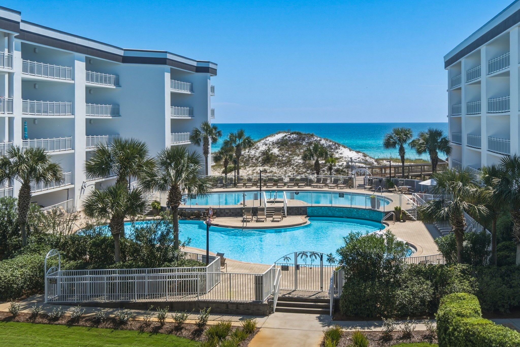 Ein Resort mit einem zentralen Pool, mehreren Balkonen und Blick auf den Ozean.